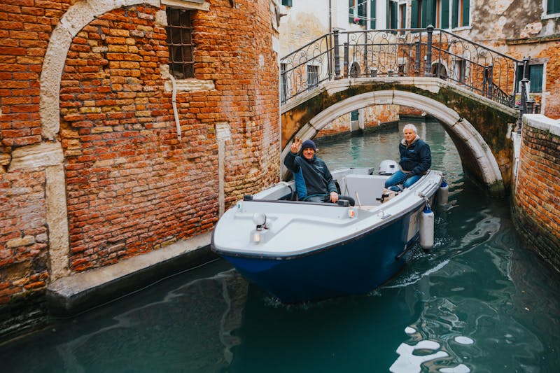 Free photo of tourists enjoy venice canal ride under historic bridge.jpeg